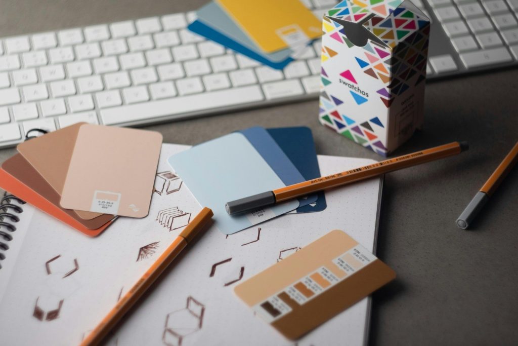 a desk with a keyboard, pencils, and various color samples